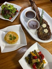 Lamb steak served with salad and mashed potato on a wooden table.