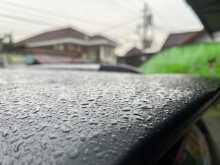 Wet car roof full of raindrop because of heavy rain weather.