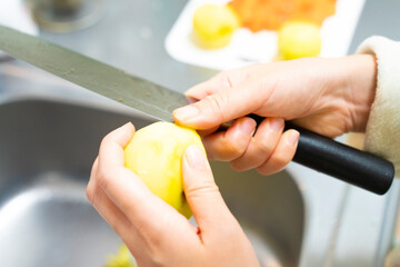 皮をむいた後のじゃがいもの芽を包丁で取り除いている写真