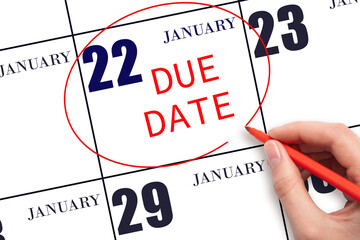 Hand writing text DUE DATE on calendar date January 22 and circling it. Payment due date