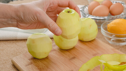 Peeled green apples close up on a wooden board, , woman hands - Powered by Adobe