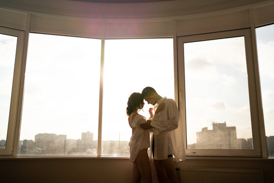 Woman and man hugging by the panoramic window at hotel. Festive morning, engagement party, happy couple, Happy Valentines day celebration, romance and love