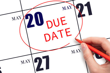 20th day of May. Hand writing text DUE DATE on calendar date May 20 and circling it. Payment due date. Business concept. Spring month, day of the year concept.