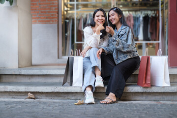 Two young beautiful hipster women sitting on urban city staircase after finished shopping.