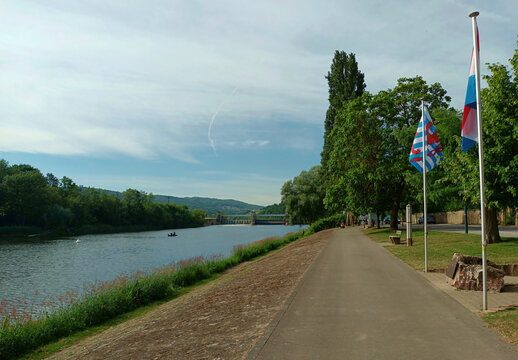 Moselpromenade in Schengen in Luxemburg mit luxemburgischer Fahne und Blick auf den Fluss Mosel. 