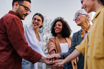 Business people putting hands in the middle, cheering to themselves.
