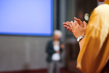 Female person clapping hands in the public, wearing a wrist watch.