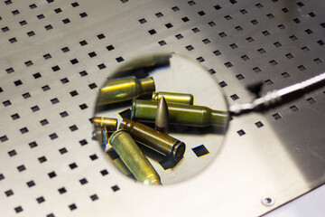 Cartridges, cartridge cases and bullets under a magnifying glass, magnifying glass close-up