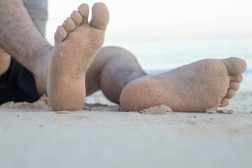 Barefoot male legs stand on the wet coastal sand on the shores of Puerto Progreso yucatan, mexico