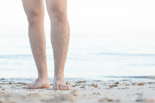 Barefoot male legs stand on the wet coastal sand on the shores of Puerto Progreso yucatan, mexico
