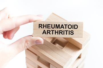 Medical concept. Rheumatoid arthritis inscription on a wooden bar in a person's hand