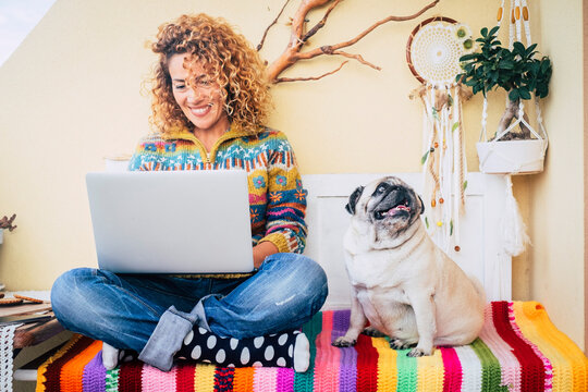 One happy woman using laptop outdoor at home sitting near her best friend dog pug and enjoying technology and friendship. Cheerful attractive female work on computer in wireless connection. Leisure