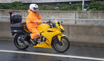A policeman in a waterproof suit rides a sports motorcycle