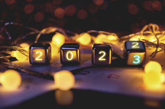 happy new year 2023 concept banner, flip calendar numbers 2022 to 2023 on steel cube blocks isolated on bokeh lights background.