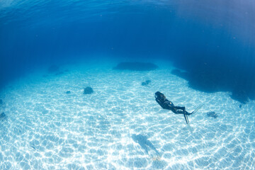 Women having fun underwater snorkeling in shallow clear waters with sunrays in the ocean