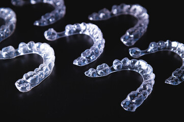 lot of aligners lie on a black background, studio shot