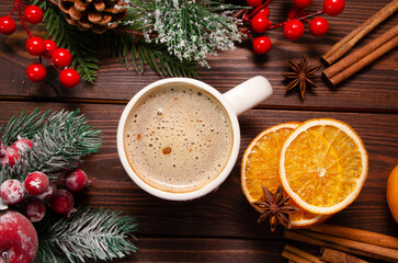 A cup of hot drink on a wooden table among Christmas decor and spicy spices. Christmas card.