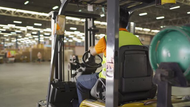 Asian worker driving Fork lift truck with pallet car vehicle in warehouse retail store industry. Rack of stock storage. Cargo in ecommerce and logistic. Depot. People lifestyle. Shipment service