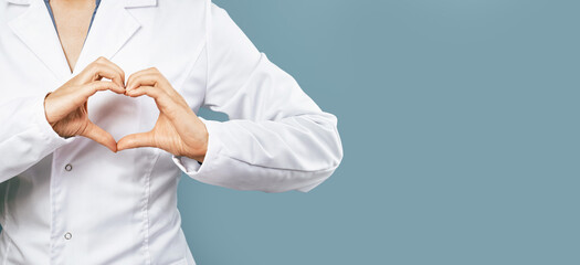Female doctor in white uniform forms a heart shape with her hands. Minimal on blue background. Banner copy space. Heart, cardiology and medical care support and assistance female health gynecology