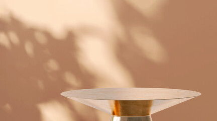 Modern and luxury gold colored round shiny pedestal steel podium in dappled sunlight in beige brown...