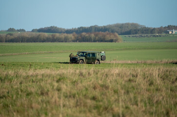 paratroopers prepare to move off in a green utility vehicle