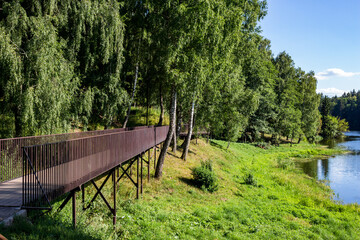Walking footbridge laid between the trees growing near the reservoir