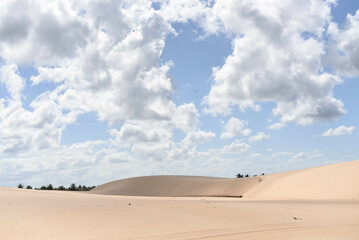 Fototapeta na wymiar Dunes covered by scattered white clouds against a beautiful blue sky on a sunny day