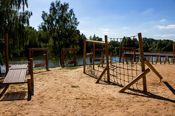 Children's sports and entertainment area built of wood on the beach near the pond