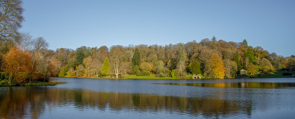 autumn afternoon sunshine illuminates woodland and island in a lake