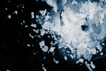 Ice, crushed on black background. Shards of crushed ice spreading away. The explosion of ice. Ice with cracks.