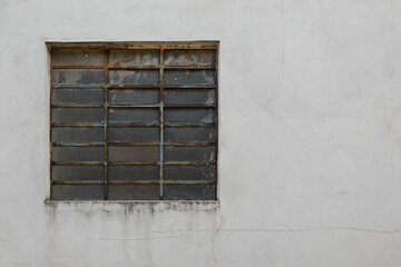 White painted house wall with glass brick stones as a window, frame rusty and weathered, background with space