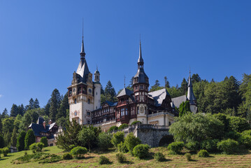 Fototapeta premium Peles Castle amongst other monuments, surrounded by pretty landscape with gardens built on terraces. It is very impressive through riches it has accumulated, Sinaia, Romania