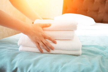 maid hands putting towel on bed in hotel room