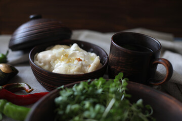 boiled hot dumplings in a clay pot with fried onions and sour cream and hot peppers
