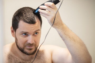 self haircut, man shaving his head with a trimmer