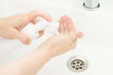 Facial skin care, cleanser face foam, Dispenser bottle in a woman's hand in bathroom