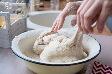 Hands knead thick dough on the kitchen table, decorated with festive decorations for Christmas and New year. Baking at home, aroma and comfort. Close-up