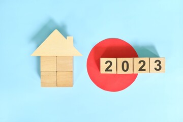 New year 2023 house or home ownership and real estate property concept. Wooden blocks on blue background with icon.	