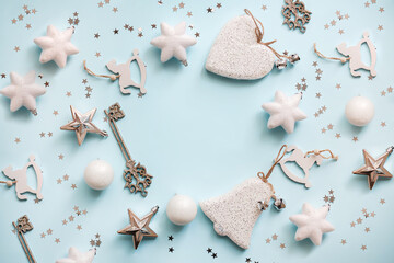 Christmas or New Year's flat lay composition of various decorative elements, sparkles and Christmas decorations in white and silver colors on a pastel light blue background. top view. copy space.