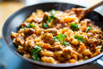 Woman cooking tasty Stew with meat and cabbage in pan on kitchen