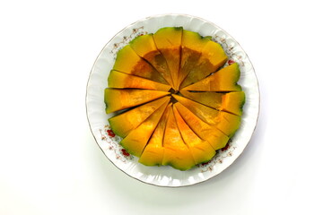 Boiled pumpkin, cut into pieces and put on a plate on a white background. Can do both savory and sweet dishes