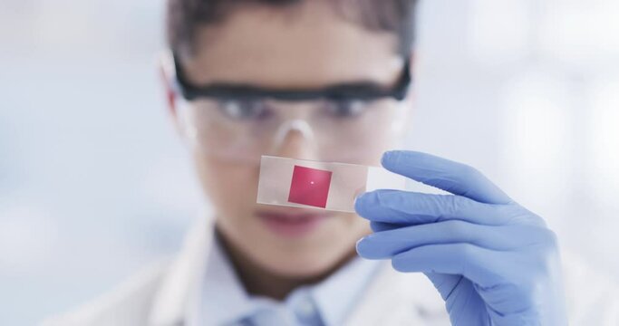 Woman, scientist and inspection of blood sample on microscopic slide, in laboratory and research. Young female, research and with dna on glass, for testing and forensic data for analysis and science