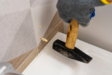  worker's hand inserts a plastic dowel pin into a drilled hole