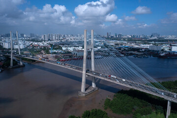 Aerial view of Phu My Bridge over Saigon river with road and river transportation on a sunny day. Ho Chi Minh City skyline can be seen in distance.