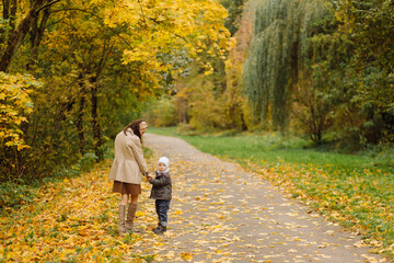 Mom and son walking and having fun together in the autumn park.