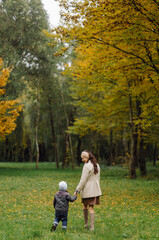 Fototapeta premium Mom and son walking and having fun together in the autumn park.