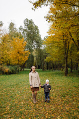 Fototapeta premium Mom and son walking and having fun together in the autumn park.