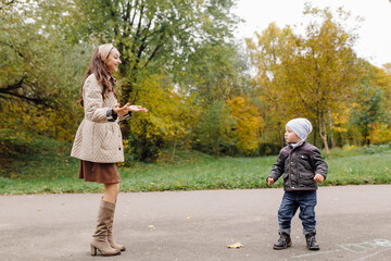 Fototapeta premium Mom and son walking and having fun together in the autumn park.