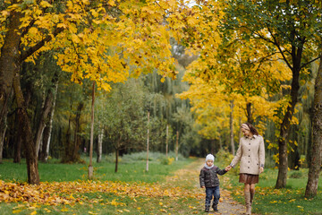 Mom and son walking and having fun together in the autumn park.