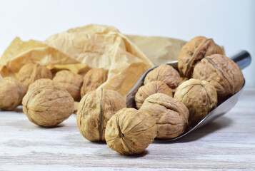 Wallnuts, full of properties, a source of protein, very healthy, in a metal shovel and behind in a kraft paper bag.
